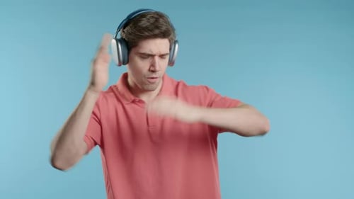 Happy Positive Man Listening Music Enjoying Dance with Headphones Blue Studio