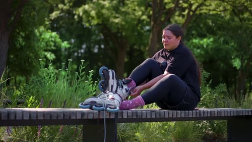 young hipster girl wearing roller skates tying laces in skate park before skating street extreme