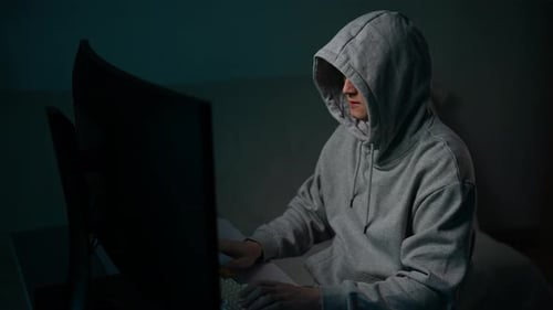 Tracking-Aufnahme eines Hackers im Hoodie, der auf der Tastatur tippt und das Passwort knackt, während er auf einem Desktop-PC sitzt