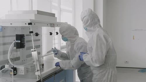 Scientist in laboratory wearing protective coverall discussing science experiment test results