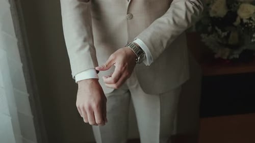 Man adjusts cuff of shirt wearing a suit