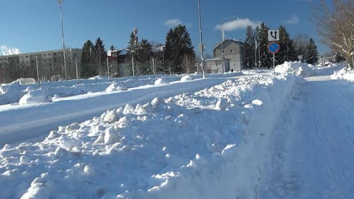 FPV or first person view of walking on a winter snow covered urban street during sunny beautiful day