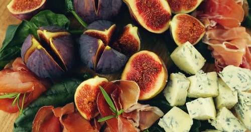 Figues, jamon, feuilles d'épinards et fromages bleus sur une planche de bois. Set de snacks.