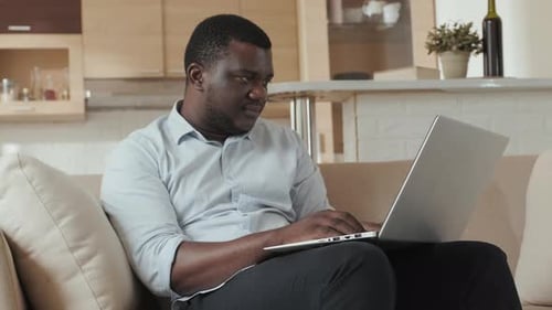 Man Working on Laptop at Home on Sofa