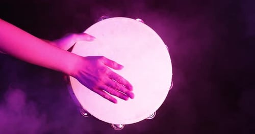 Hand Playing Tambourine in Purple Smoke