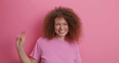 Glückliche lockige europäische Frau tanzt sorglos macht Disco-Geste hat fröhlich