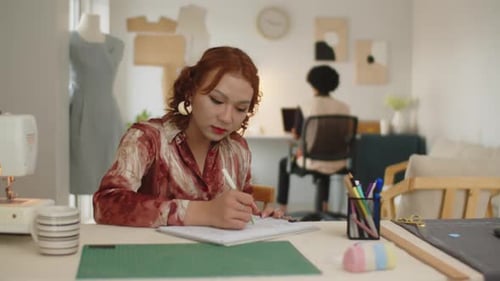 Seamstress Drawing Sketch of Dress in Sewing Atelier