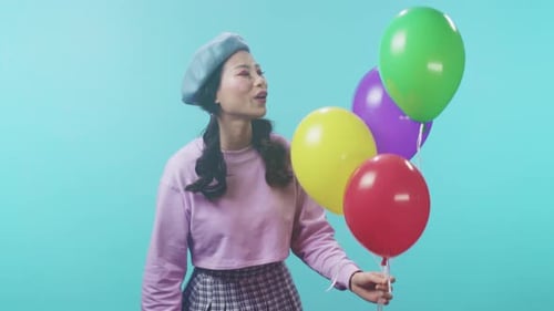 Smiling woman with balloons against a bright blue background