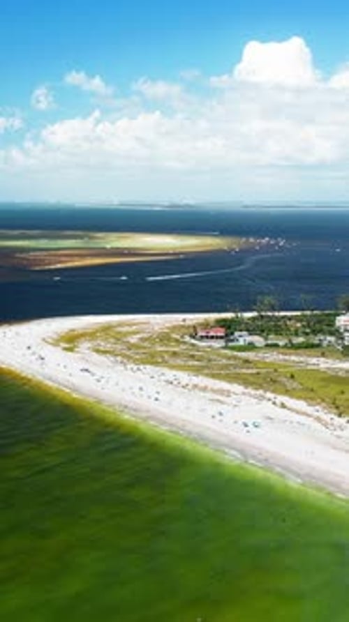 Curved sandy shoreline with boats near glowing offshore sandbars