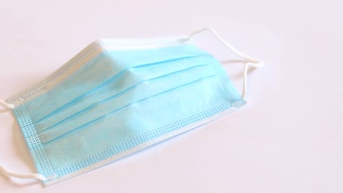 Man's hand picking up a blue cotton face mask.