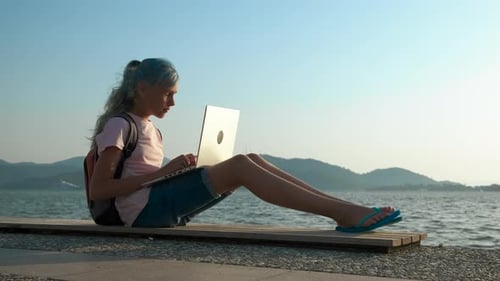 Woman Using Laptop at Lake Shoreline