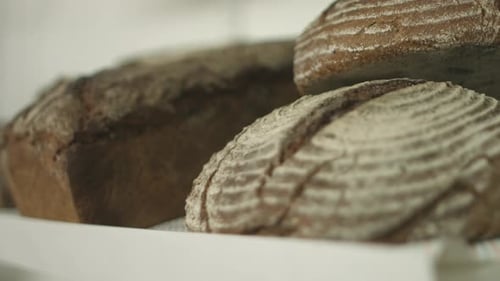 Close up of 3 whole grain bread loafs lying at a shelf on a farmers market. Shallow depth of field w
