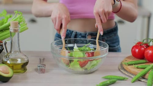 Young Adult Mixing a Fresh Salad in Kitchen