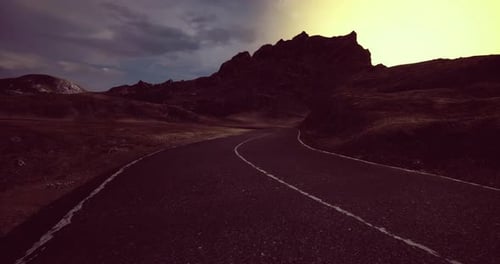 Winding Road Leading Toward Majestic Mountains at Dawn with Vibrant Colors