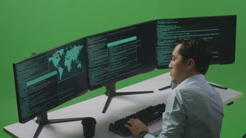 Side View Of Bored Asian Man Developer Write Code With Multiple Computer Screens In Green Screen