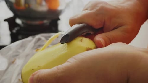 peeling potatoes close up with a potato peeler