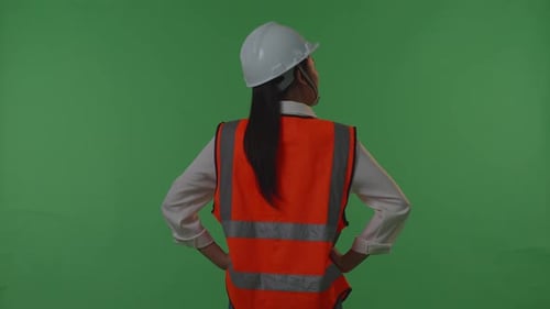Back View Of A Female Engineer Looking Around While Standing With Arms Akimbo In The Green Screen