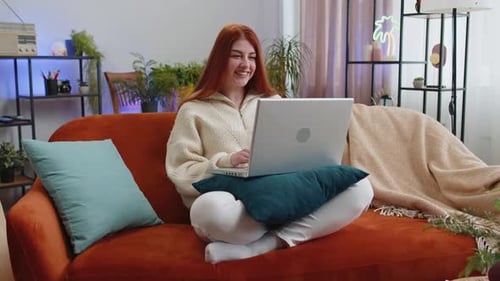 Woman Chatting on Laptop from Home on Sofa