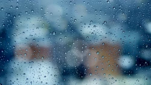 close up of rain drops poring down on window glass. raining day background