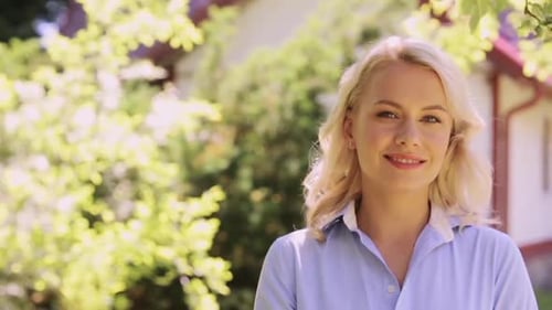 Smiling blonde woman in garden setting with trees