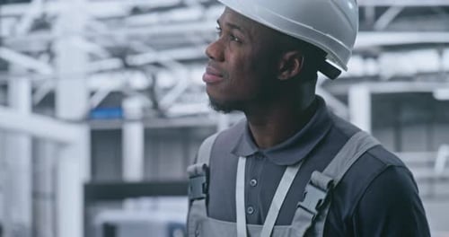 Male Industrial Engineer Moves Through Futuristic Factory Hall Closely Observing Robotic Systems