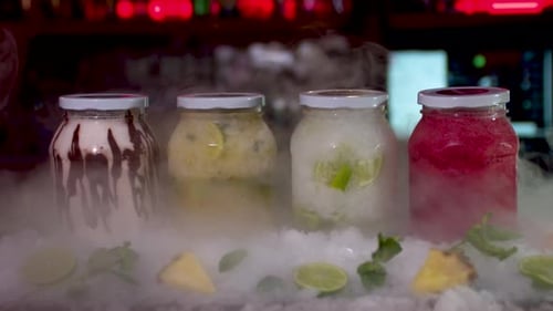 Dry Ice Reveal Of Colourful Frozen Smoothie Jars On Bar. Dolly Forward, Slow Motion