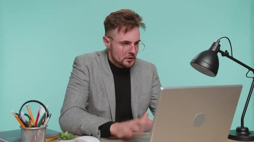 Man Frustrated While Working at Desk on Laptop