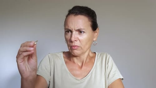 Disgusted Woman Looks at a Coin in her Hand