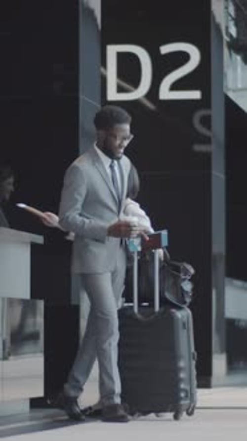 Businessman Completing Check-In at Airport, then Walking away with Luggage