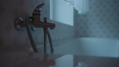 Leaky Faucet Dripping Water in Dim Bathroom