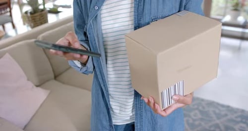 Person Holding Package and Using Smartphone Indoors