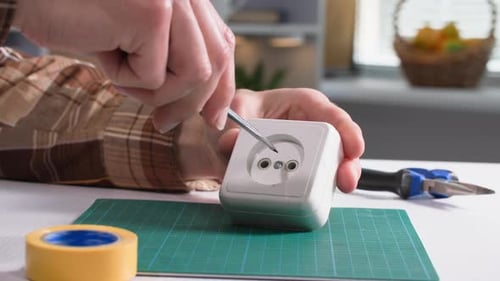 Man with a Screwdriver in His Hands Unwinds an Electrical Outlet for Troubleshooting Closeup
