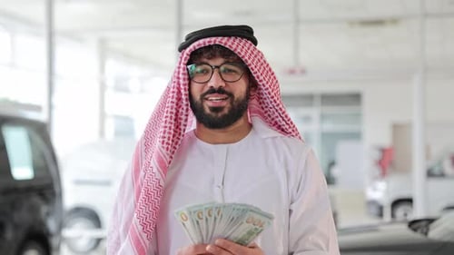 Arab Businessman Holding Us Dollar Bills in a Car Showroom