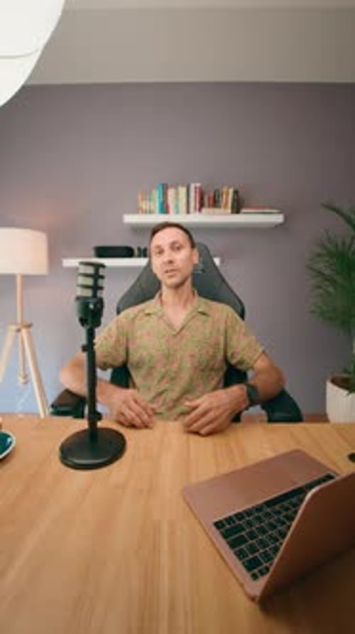 A Man Records a Podcast at Home with a Laptop and Microphone Showing a Professional Setup