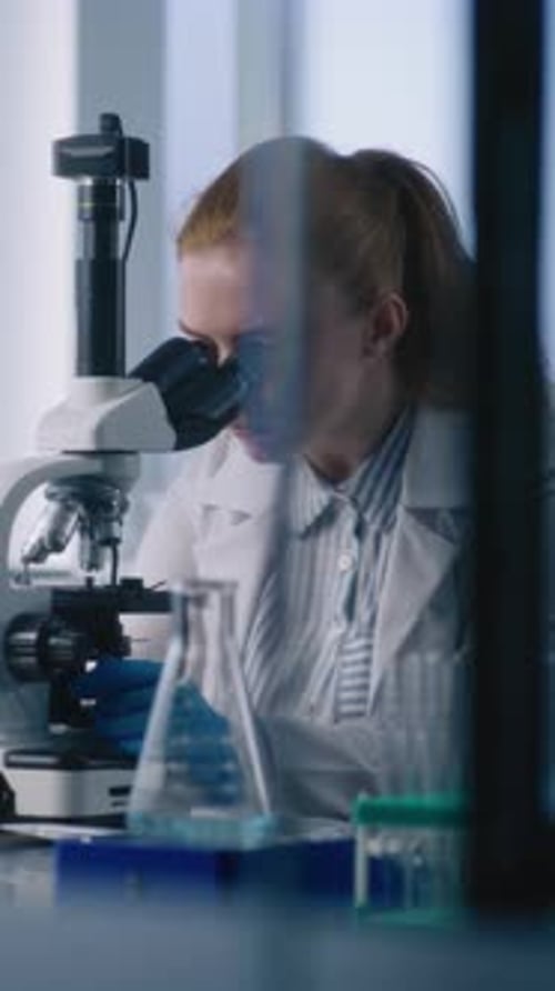Female Scientist Works with Microscope in Modern Lab