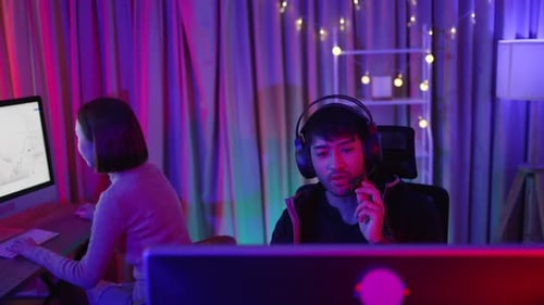 Two Young Adults Working with Computers at Night