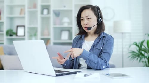 Woman Using Laptop and Headset for Video Conference