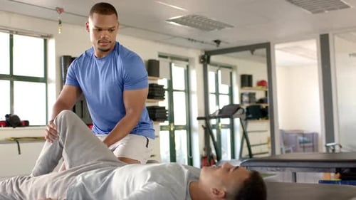 Man Stretching Patient's Leg in Physical Therapy Office