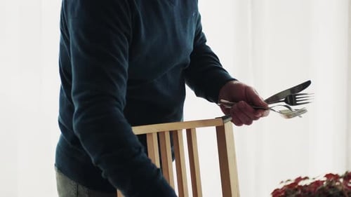Man Sets Table in Bright Dining Room