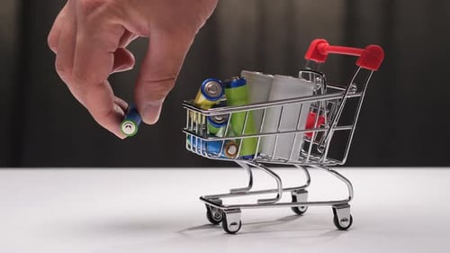Hand Places Battery into Miniature Shopping Cart