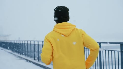 Man Athlete in a Bright Sweater Runs Down the Street in Winter