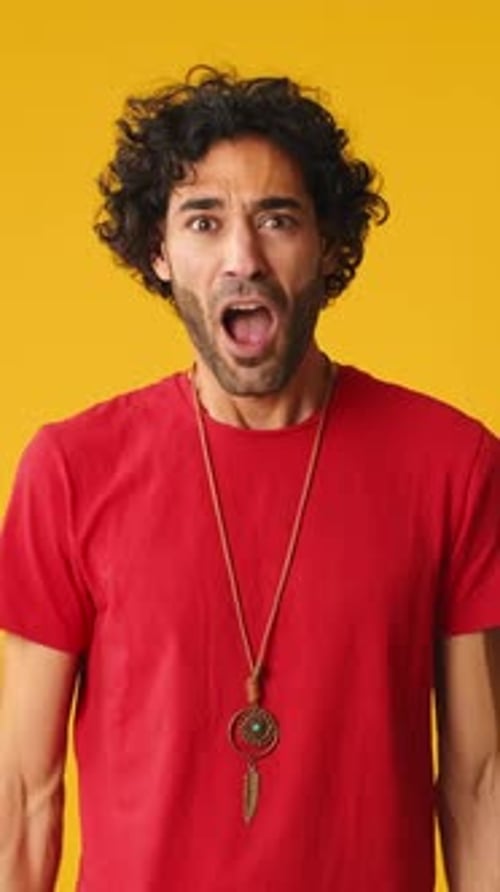 Wonder man put his hands on his head looking at camera isolated on yellow background in studio