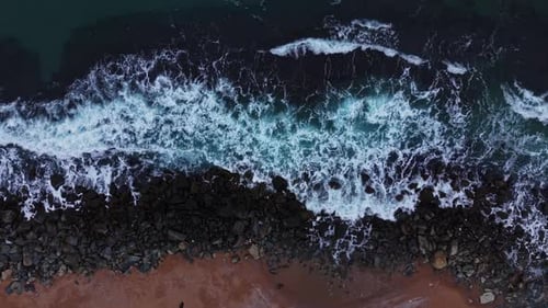 Waves Crashing on Rocky Shoreline: Aerial Coastal View