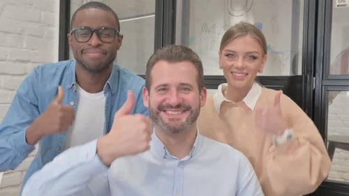 Smiling Professionals Giving Thumbs Up in Modern Office