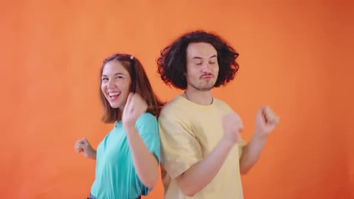 Cheerful Friends Dancing Together in Front of Orange Backdrop