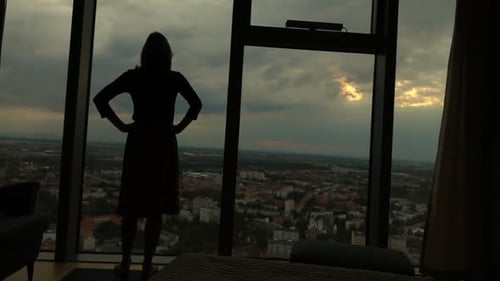 Woman Silhouette Looking Out Over City at Sunset