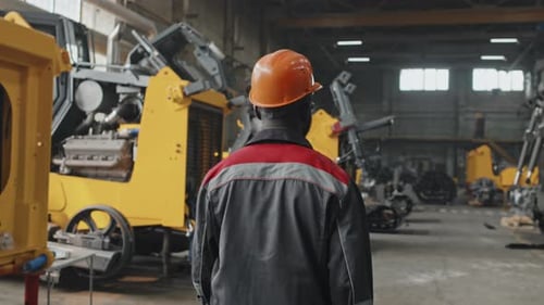 Ouvrier d'une usine de tracteurs marchant sur le lieu de travail