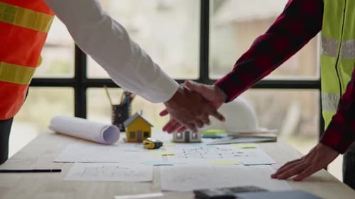 Architects Reviewing Blueprints Shake Hands on Deal