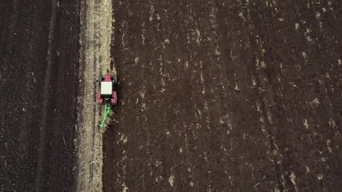 Red tractor plowing the field in Ukraine