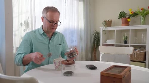 Man Preparing Tea at Table in Sunny Room